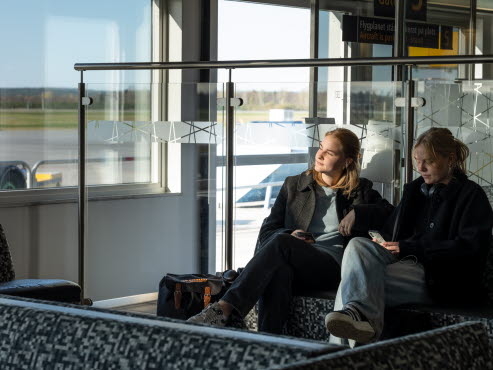 Two female travelers are sitting in a waiting area.