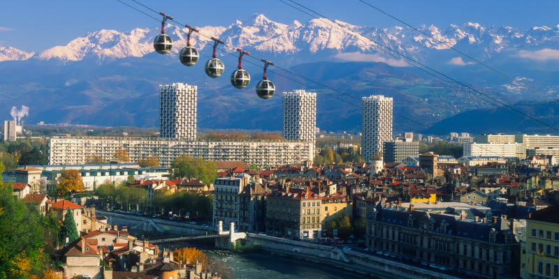 Grenoble med flod, linbana och alper i bakgrunden