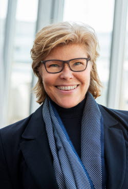 A photo of Katrin Bäckman, a blond woman with glasses and a blue scarf