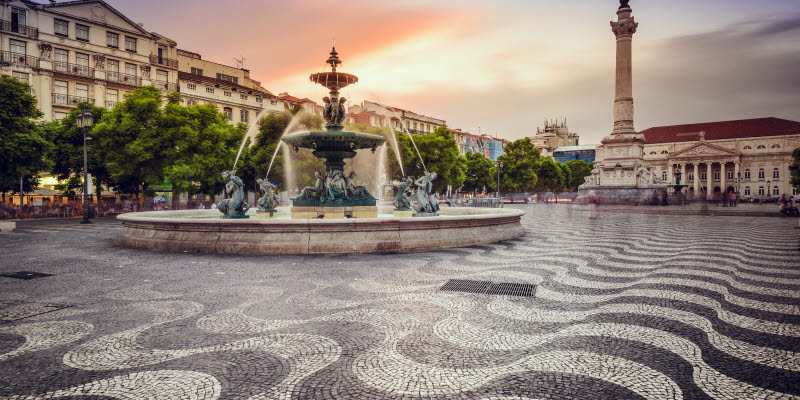 Torg och fontän i Lissabon i skymning 