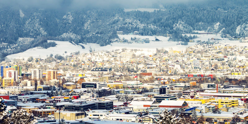  123/5000 Innsbruck, Österrike. Flygfoto över Innsbruck, Österrike en vintermorgon, med snö och berg i bakgrunden.