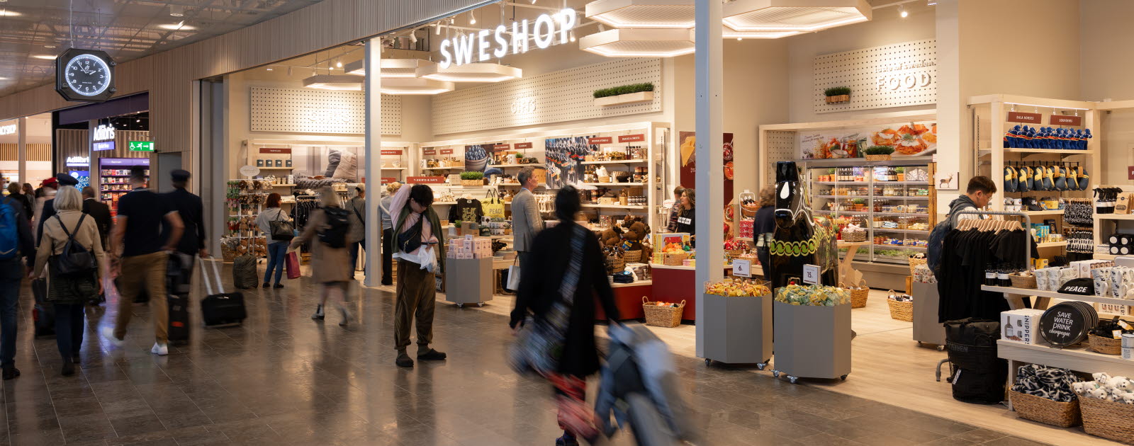 People with luggage walking in front of Sweshop.