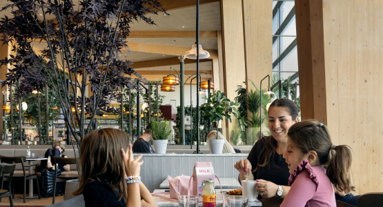 Woman and two children are eating at restaurant in airport