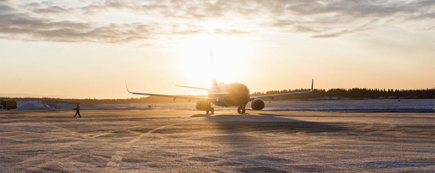 Flygplan i motljus vid soluppgång på frostig asfalt.