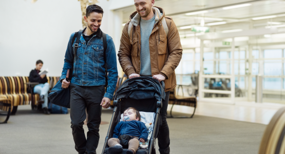 Two male travellers with stroller in airport terminal