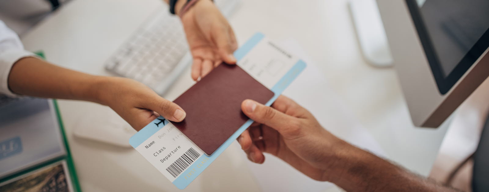 Kvinnas armar sträcker ett pass och boardingkort till en mans hand.