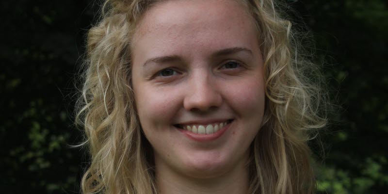 Woman with blonde curly shoulder length hair smiling at camera.