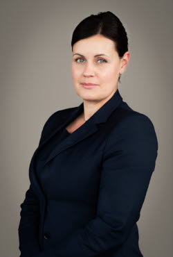 Woman with hair in an updo dressed in suit jacket smiling slightly at the camera.