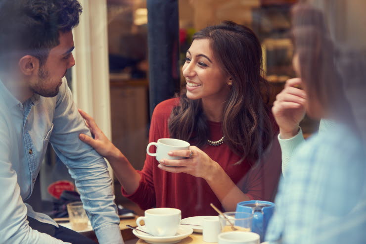 A group of three are drinking coffee and having a converesation.