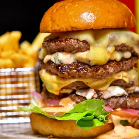 Hamburgare med fyra biffar, ost, dressing, sallad och lök.