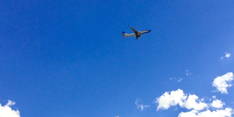 Airplane up in a blue sky above white clouds. Photo: Hans Uhrus