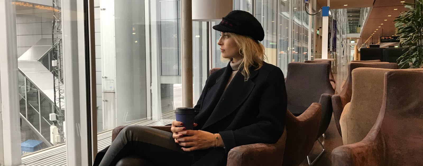 Cissi Forss sitter i en fåtölj på Arlanda med en kaffemugg och kollar ut mot flygplanen.