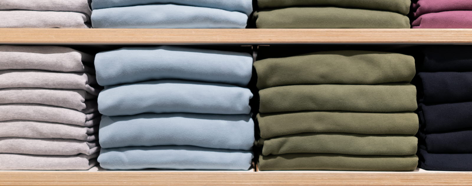 Stacks of folded clothes on wooden shelves.