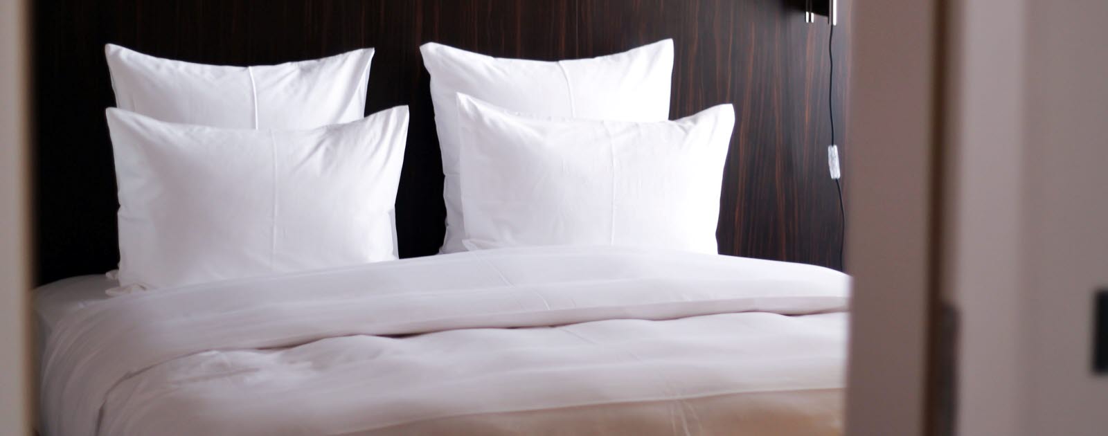 Bed made with white sheets and four pillows.