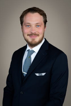 Man with short hair and beard dressed in suit and tie smiling at the camera.