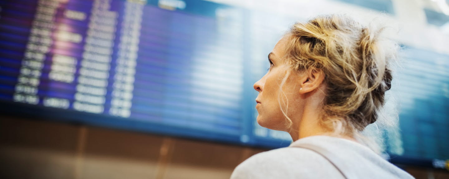 En person tittar på tavla med avgångar eller ankomster på Arlanda