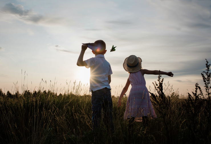 Girl and boy throwing airplane