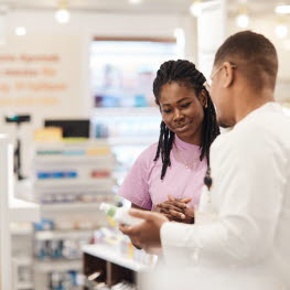 Woman looking at product held by man dressed in a white robe.