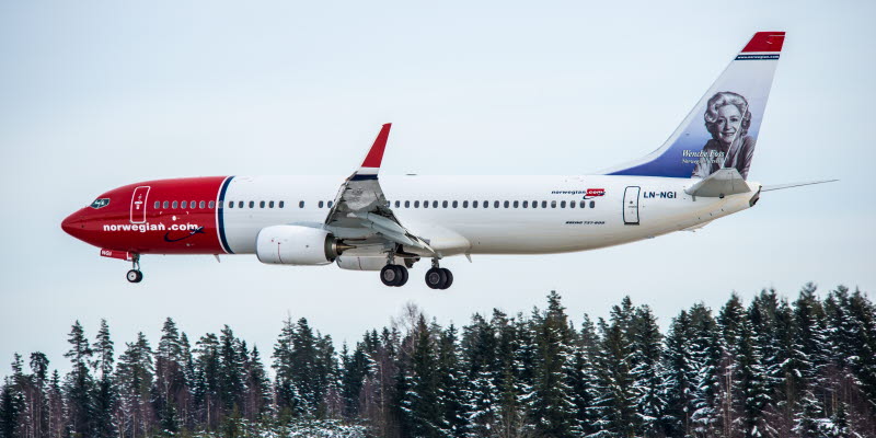Norwegian flygplan landar ovanför snötäckta granar