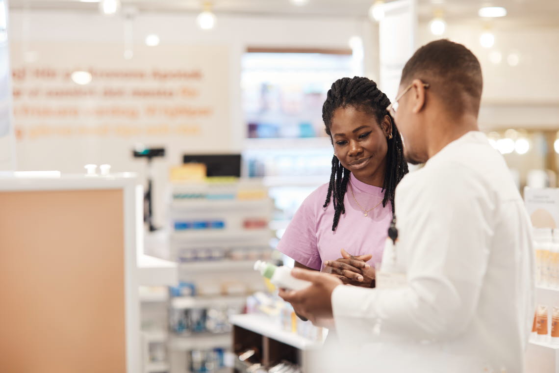 Woman looking at product held by man dressed in a white robe.