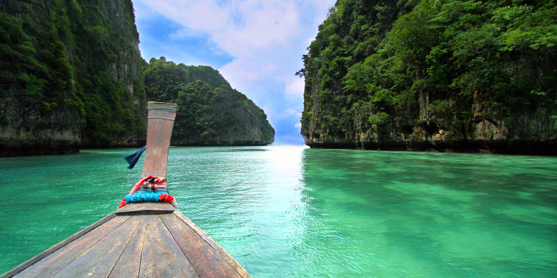 Båt på turkost vatten omgiven av vacker natur, Phuket