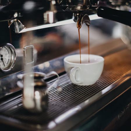 Kaffe rinner från espressomaskin in i en kopp.