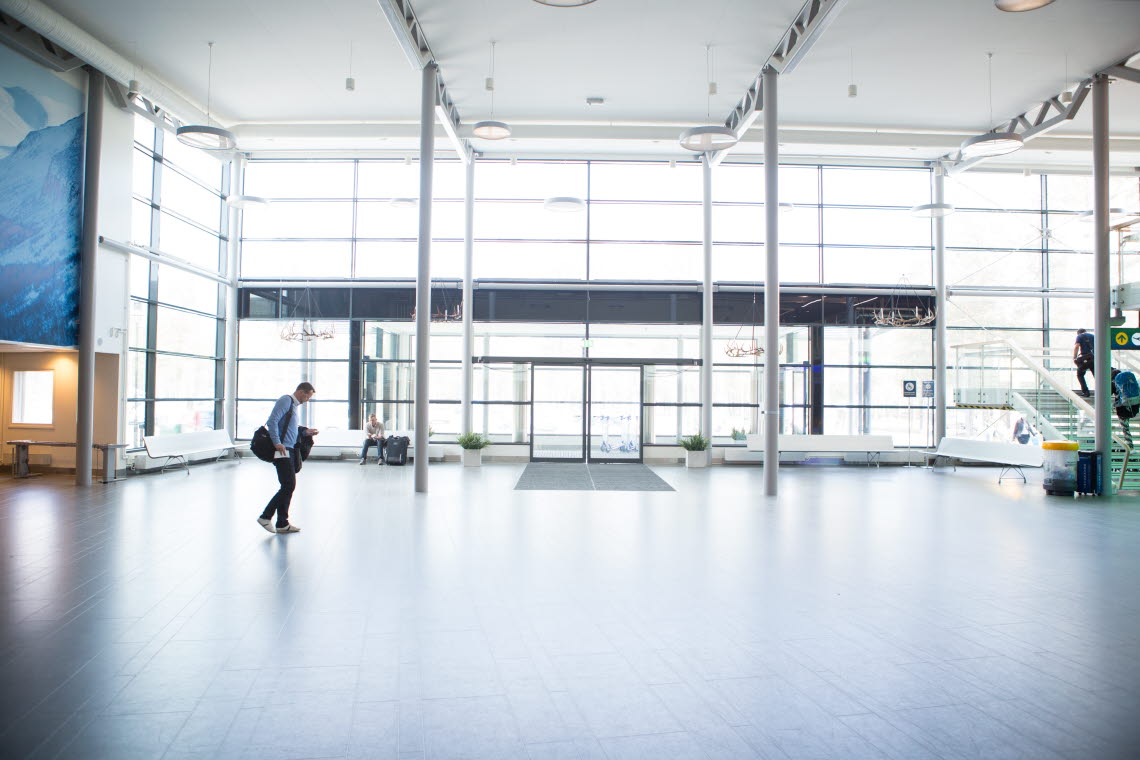 Man walks across empty entrence hall in front of panorama windows.