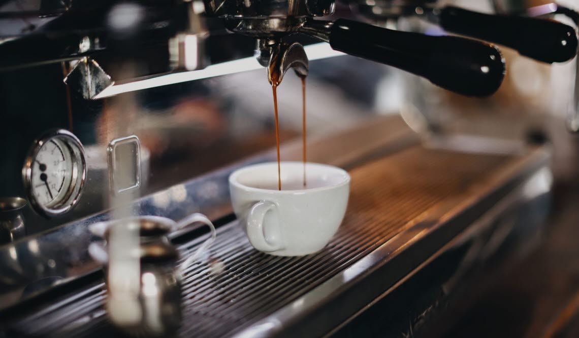 Kaffe rinner från espressomaskin in i en kopp.