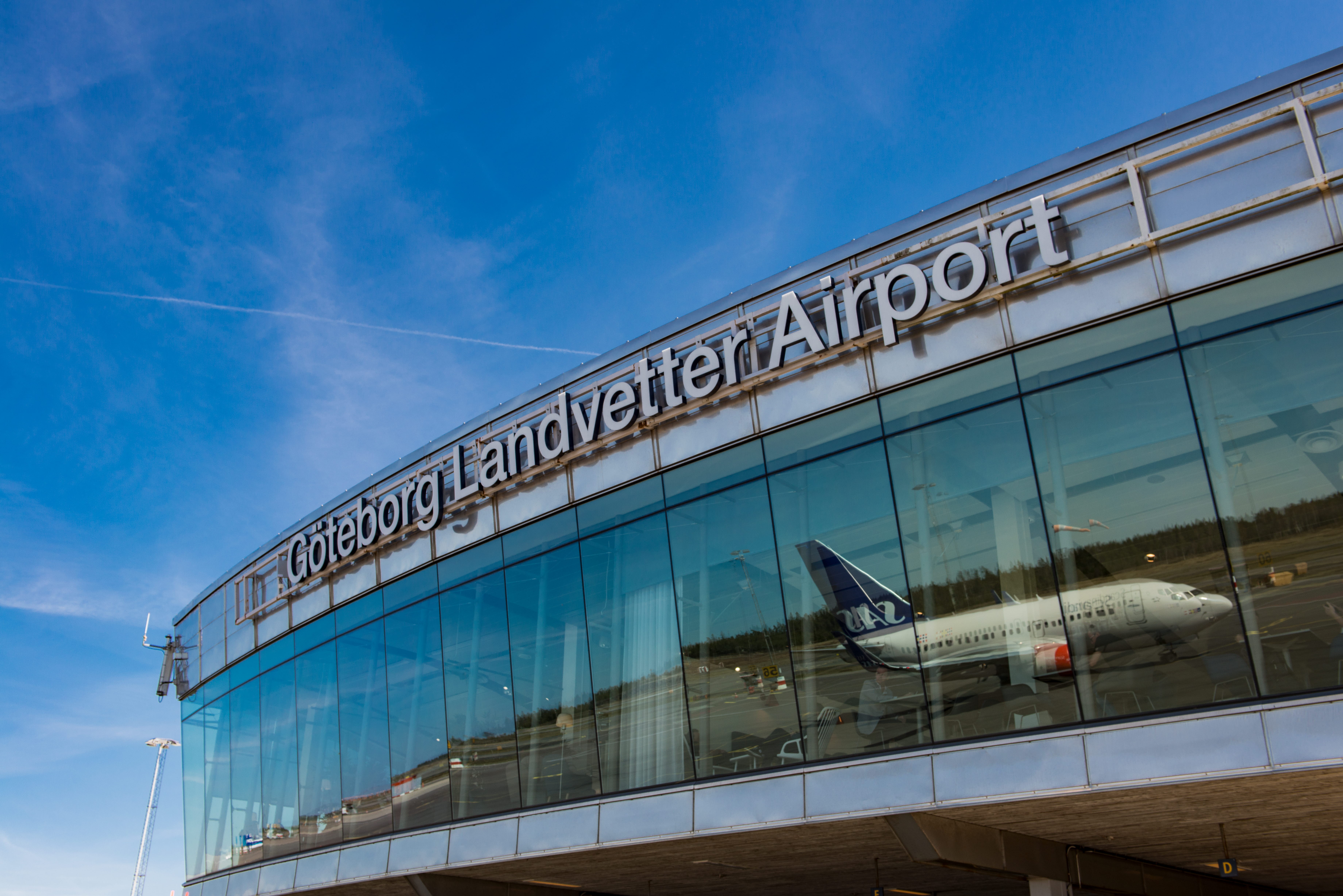 Göteborg Landvetter Airport med blå himmel och ett flygplan som speglar sig i glaset