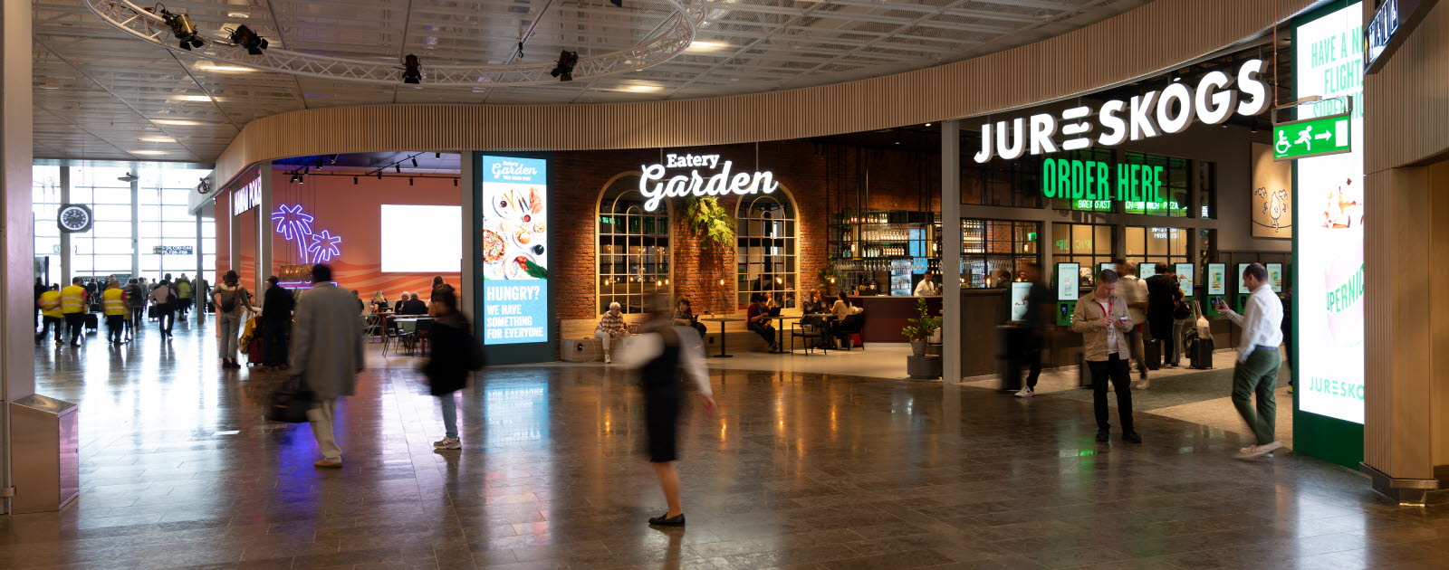 Open area with three restaurant entrances and people walking around.