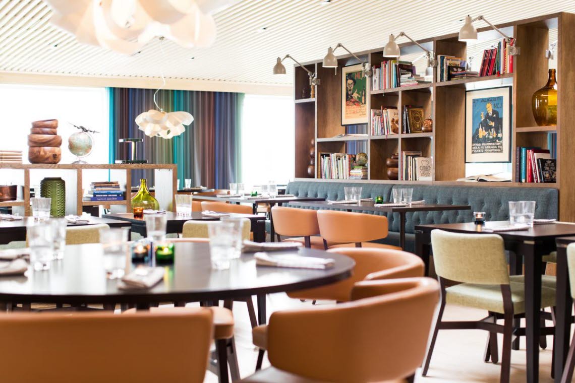 Restaurant interior with tables, chairs, sofas and bookshelves.