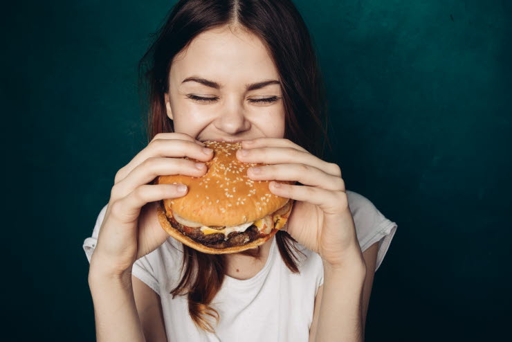 En kvinna som äter en hamburgare.
