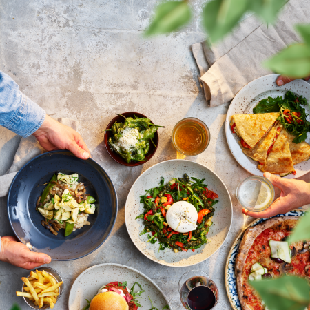 Plates and bowls with colourful meals against a concrete background.
