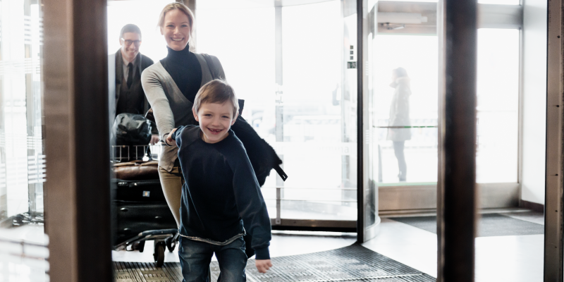 Pojke håller kvinna i handen vid ingången till terminal på Arlanda