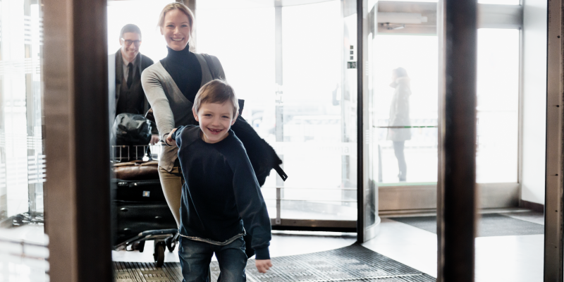 Boy holding woman's hand at the entry of a terminal at Stockholm Arlanda