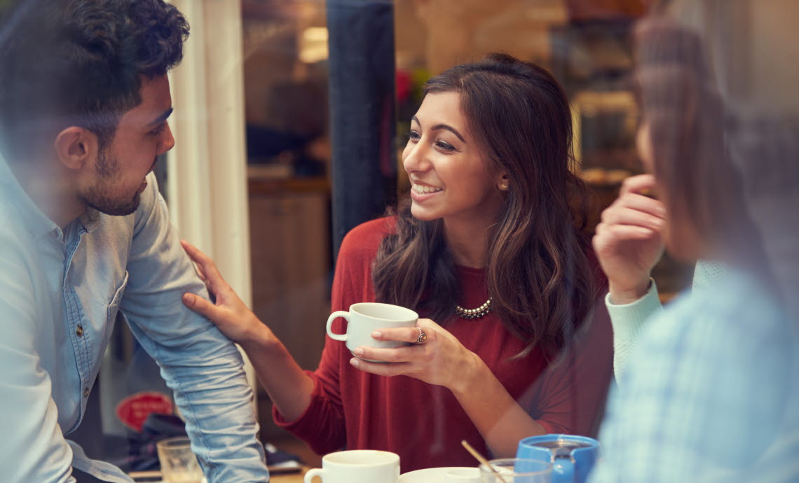 A group of three are drinking coffee and having a converesation.