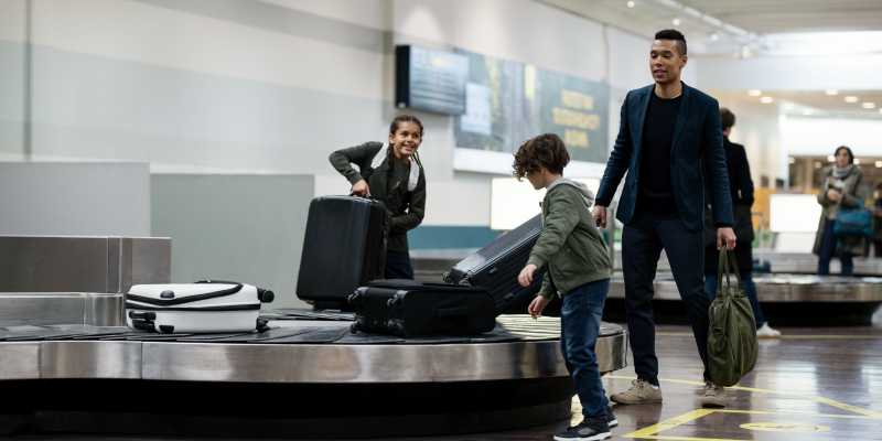 En man och två barn vid ett bagageband