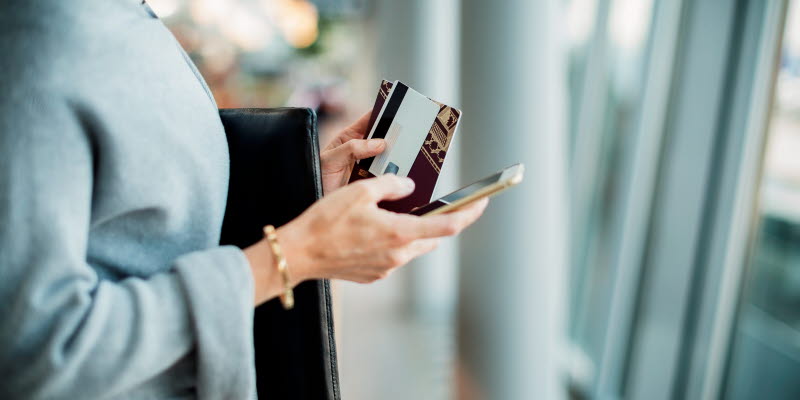 Händer som håller pass och en mobiltelefon
