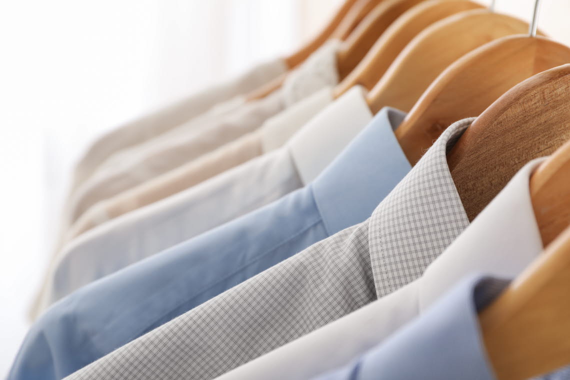 Close up of dress shirts in light colours on hangers.