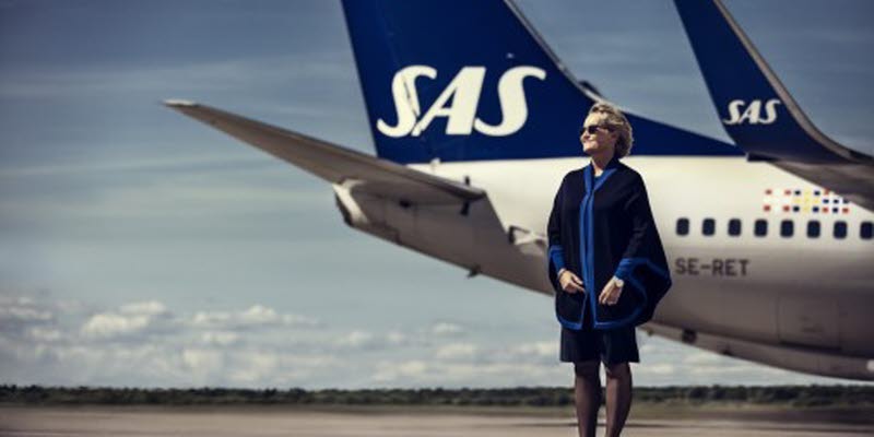 An SAS employee in front of a SAS plane on the runway