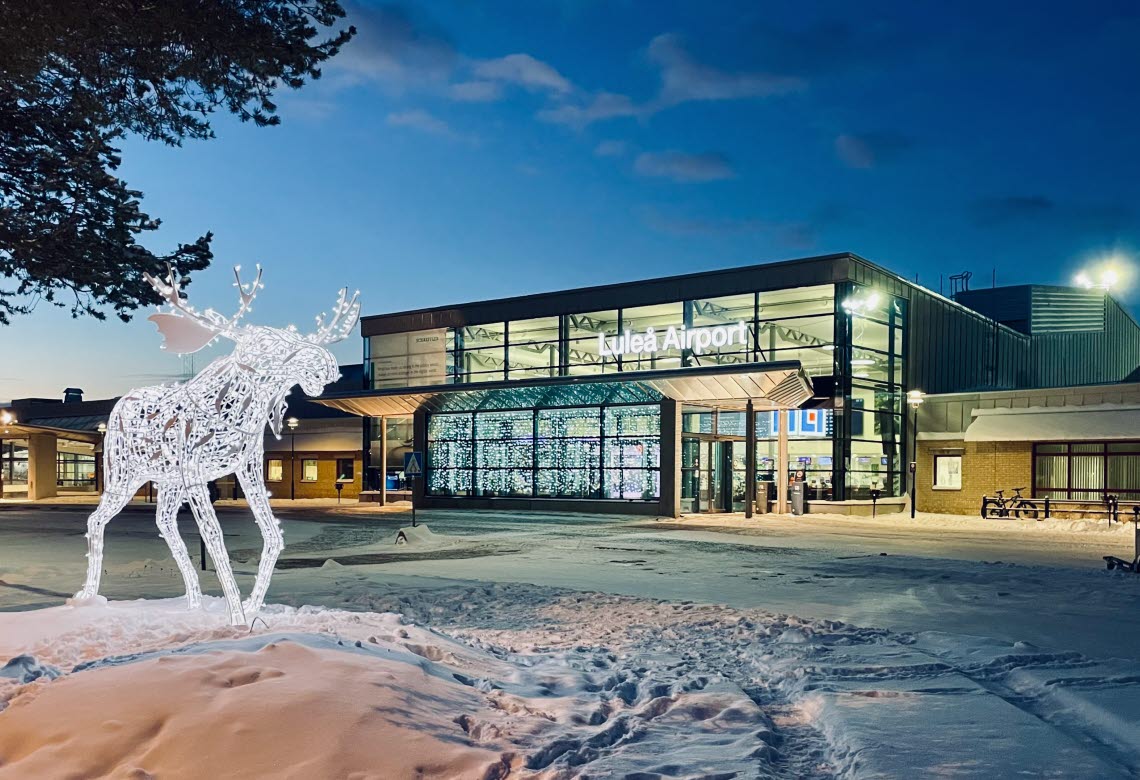 Entrence to Luleå Airport at dusk, with snow on the ground and an elk made of lights across the street.