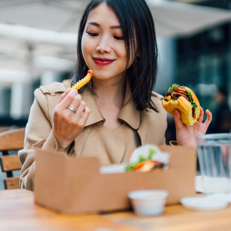 Kvinna äter hamburgare och pommes frites
