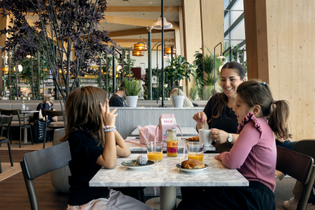 Woman and two children are eating at restaurant in airport