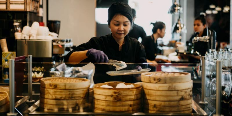Kvinna lägger upp mat i restaurangkök