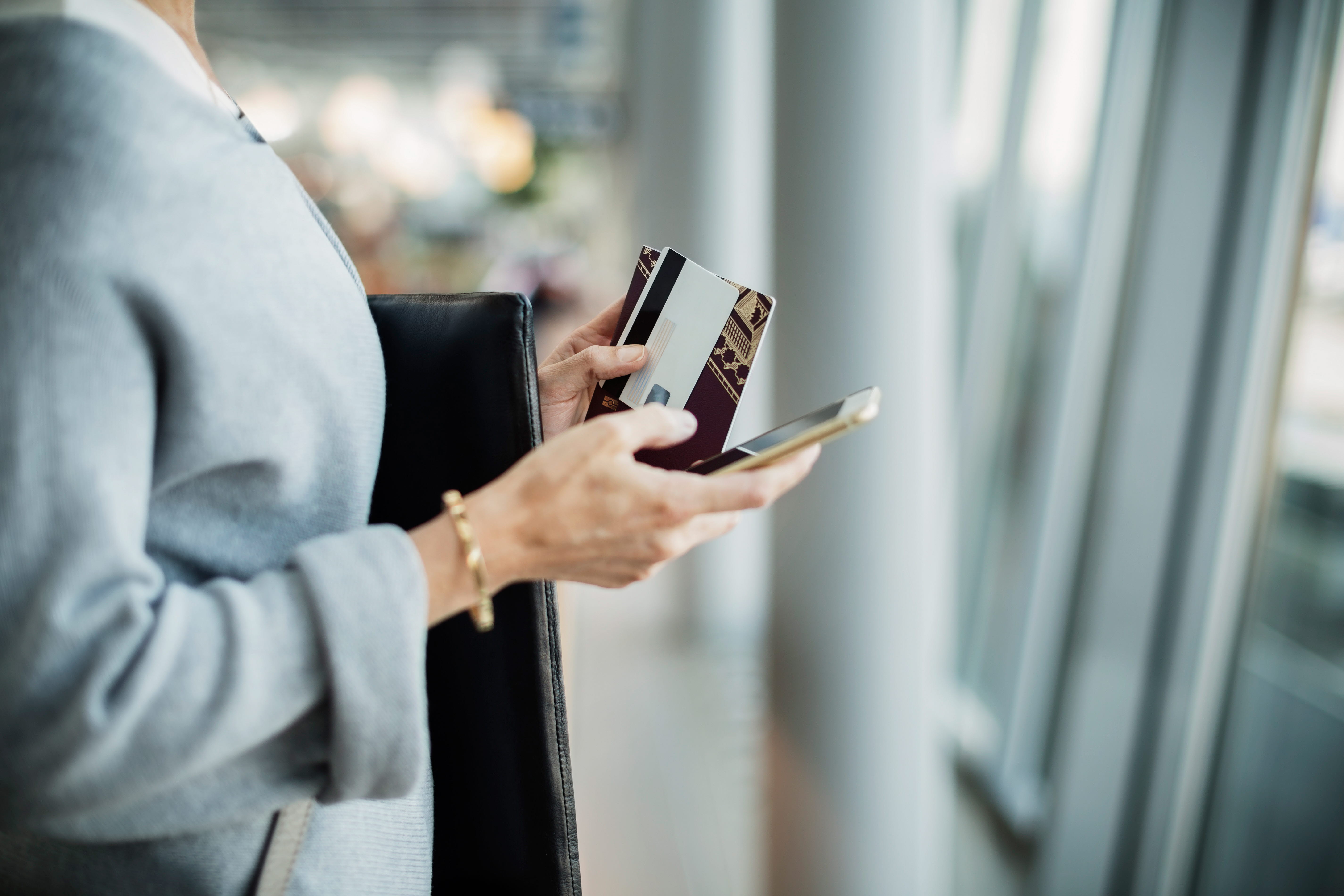 Händer som håller pass och en mobiltelefon
