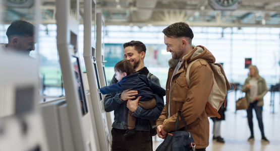 Två män och ett barn använder check-in automaten