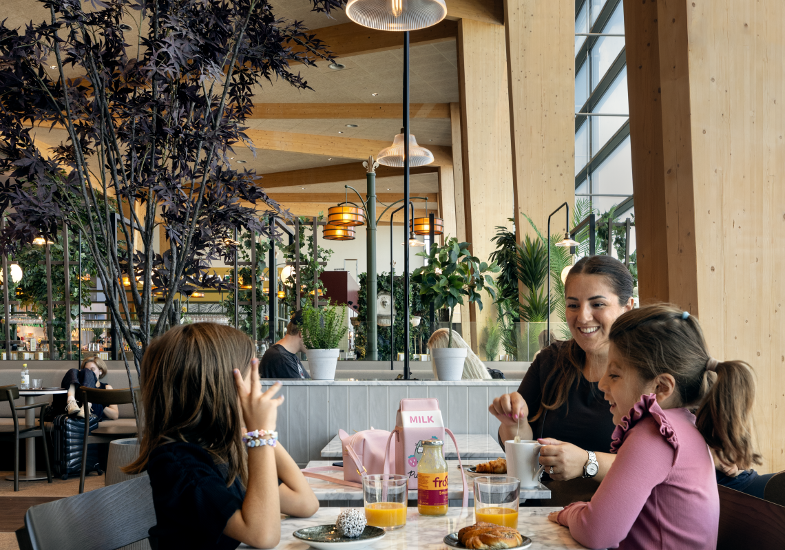 Woman and two children are eating at restaurant in airport