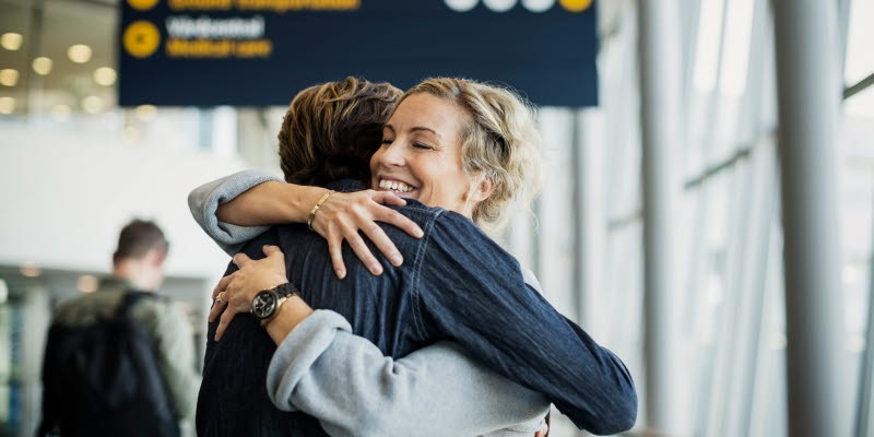Kvinna kramar en resenär på flygplatsen