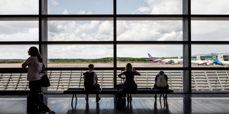 Människor vid ett fönster i SkyCity Arlanda överblickande flygplan på startbana