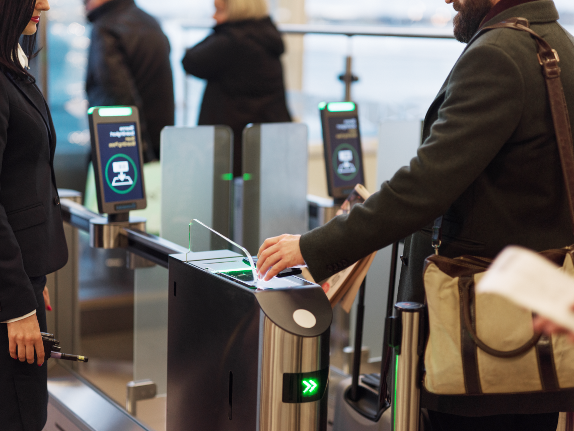 Man håller mobil över självscannings-grind för boarding pass.